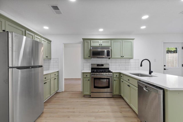 2310 Raintree Path, Round Rock, TX 78664 - kitchen with appliances with stainless steel finishes, green cabinetry, a sink, a peninsula, and light countertops