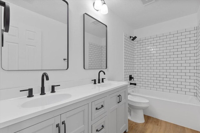 2310 Raintree Path, Round Rock, TX 78664 - full bath with double vanity, bathing tub / shower combination, wood finished floors, and a textured ceiling