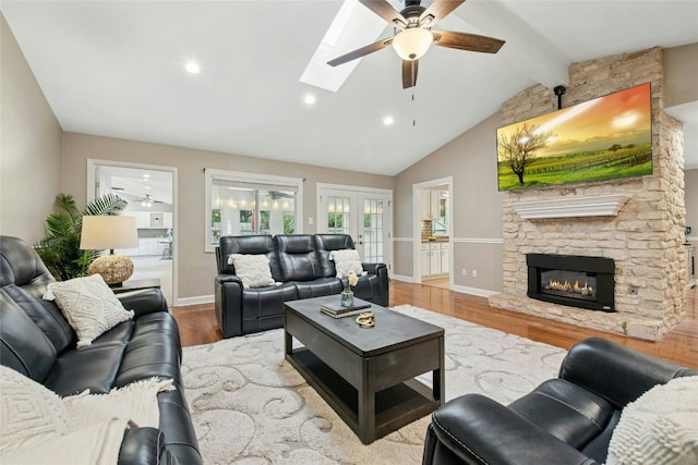2627 Oak Meadow Dr, Round Rock, TX 78681 - living area featuring ceiling fan, wood finished floors, baseboards, a stone fireplace, and a skylight