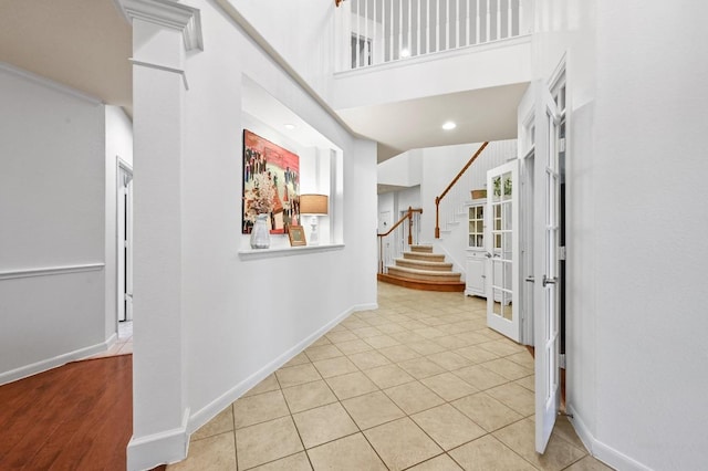 tiled foyer with stairs, baseboards, and a high ceiling