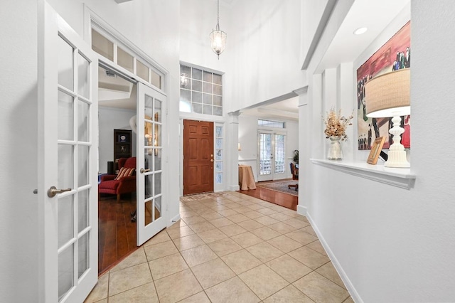 tiled foyer entrance featuring french doors, baseboards, and a high ceiling