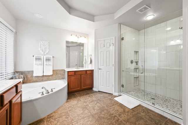 bathroom with a stall shower, vanity, a garden tub, and a chandelier