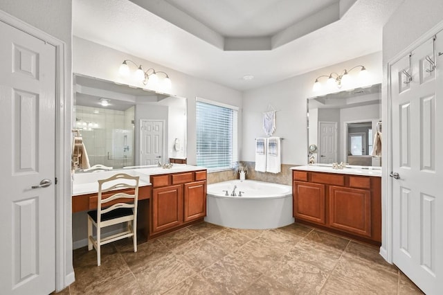 bathroom featuring a shower stall, a garden tub, two vanities, and a raised ceiling