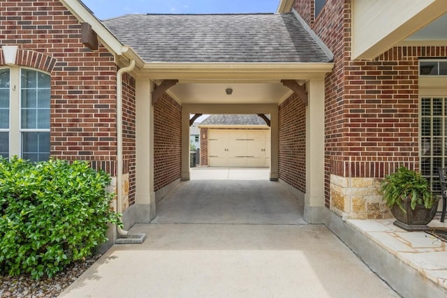 entrance to property with brick siding, driveway, and a shingled roof