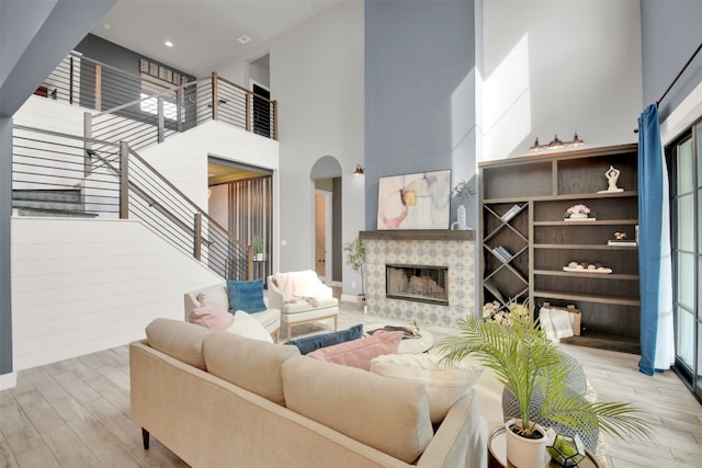 1506 Fox Sparrow Trl, Cedar Park, TX 78613 - living room with a high ceiling, arched walkways, wood finished floors, stairs, and a tiled fireplace