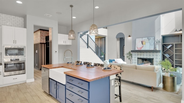 1506 Fox Sparrow Trl, Cedar Park, TX 78613 - kitchen with stainless steel appliances, butcher block counters, a sink, white cabinetry, and a kitchen bar