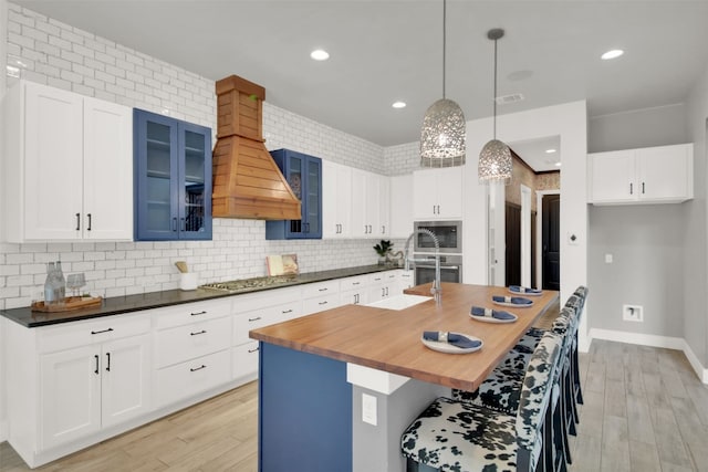 1506 Fox Sparrow Trl, Cedar Park, TX 78613 - kitchen with stainless steel appliances, butcher block countertops, custom exhaust hood, light wood-type flooring, and recessed lighting
