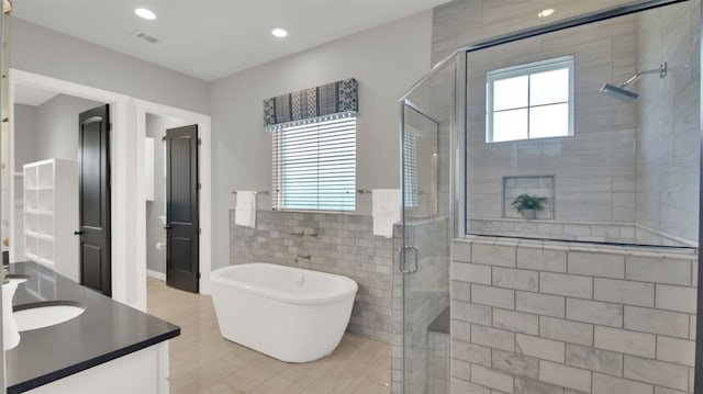 1506 Fox Sparrow Trl, Cedar Park, TX 78613 - bathroom featuring vanity, a stall shower, a freestanding bath, tile walls, and recessed lighting