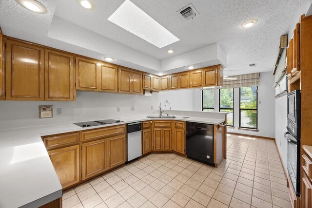 6820 N Cypress Pt Unit 22, Austin, TX 78746 - kitchen with black appliances, a skylight, a peninsula, light countertops, and brown cabinets