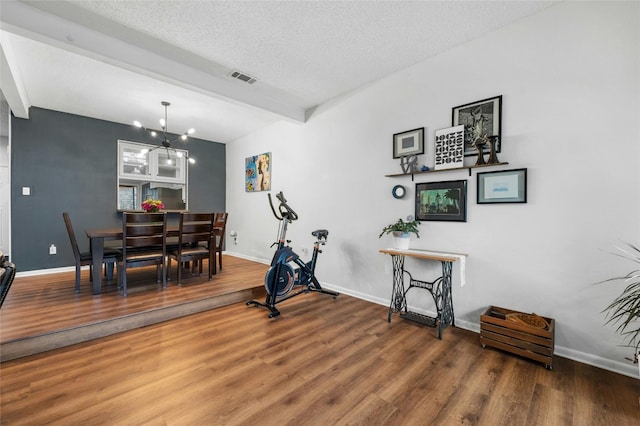 dining area with wood finished floors, baseboards, a chandelier, beamed ceiling, and a textured ceiling