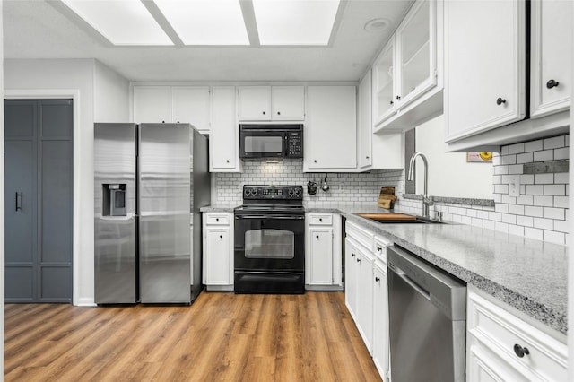 kitchen with black appliances, a sink, white cabinetry, and decorative backsplash