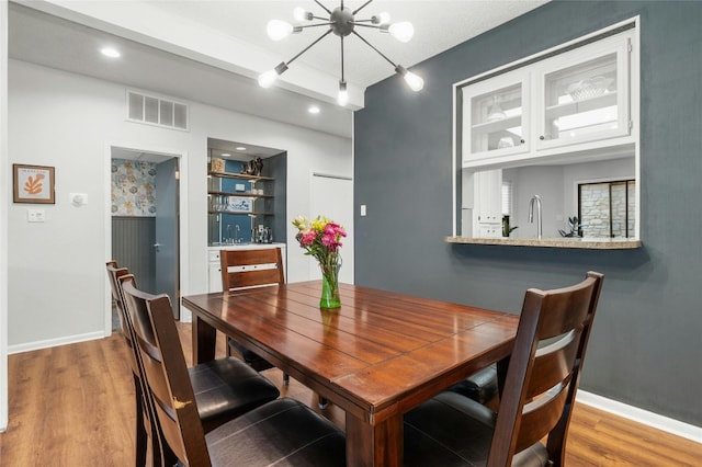 dining space featuring wood finished floors, a chandelier, and baseboards