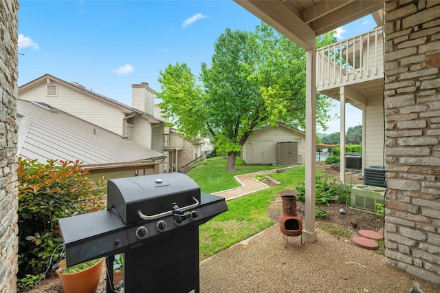 view of green lawn featuring a shed, an outbuilding, a balcony, central air condition unit, and a patio area