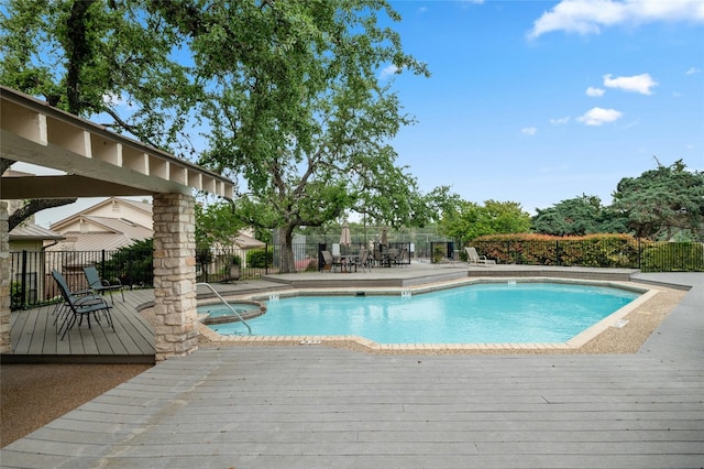 view of pool with a deck, fence, and an in-ground hot tub