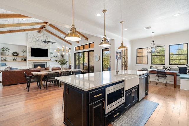 705 Highland Overlook, Georgetown, TX 78633 - kitchen with stainless steel appliances, open floor plan, a stone fireplace, dark cabinets, and recessed lighting