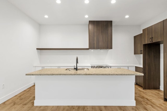 4407 Merle Dr Unit A, Austin, TX 78745 - kitchen with a sink, an island with sink, light wood-style flooring, dark brown cabinets, and baseboards