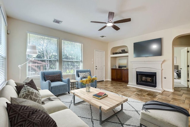 409 S Frontier Ln, Cedar Park, TX 78613 - living room with built in shelves, a ceiling fan, arched walkways, a fireplace with raised hearth, and baseboards