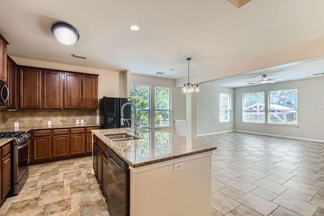 409 S Frontier Ln, Cedar Park, TX 78613 - kitchen with black appliances, decorative backsplash, light stone countertops, a kitchen island with sink, and open floor plan