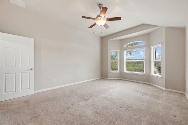 carpeted empty room with vaulted ceiling, baseboards, and a ceiling fan