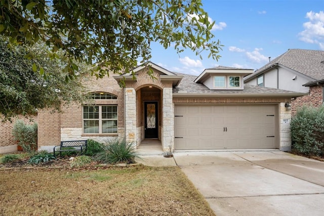 traditional home with stone siding, concrete driveway, an attached garage, and roof with shingles
