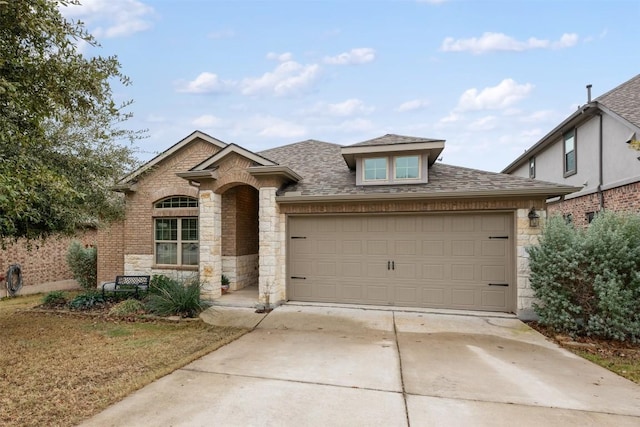 french country inspired facade featuring stone siding, an attached garage, concrete driveway, and roof with shingles