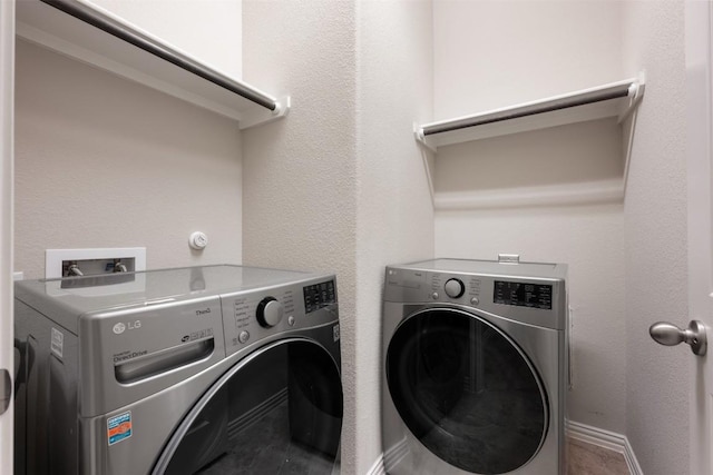 clothes washing area featuring separate washer and dryer and baseboards