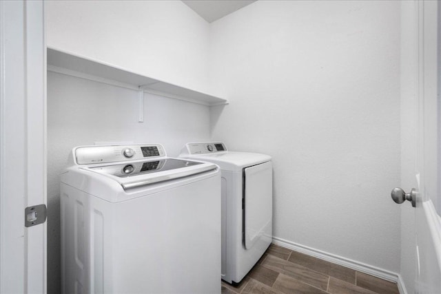 washroom featuring washing machine and dryer, baseboards, and wood finish floors
