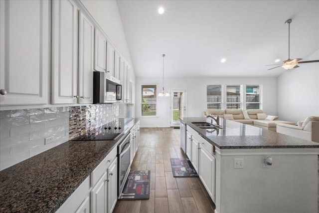 kitchen featuring stainless steel microwave, a sink, dark wood-type flooring, decorative backsplash, and healthy amount of natural light