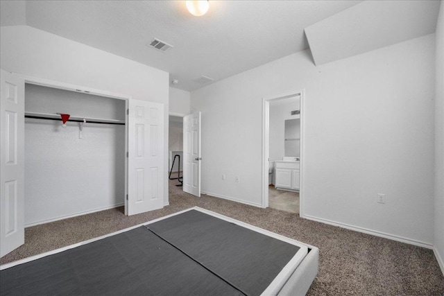 unfurnished bedroom featuring carpet flooring, a closet, ensuite bath, and baseboards