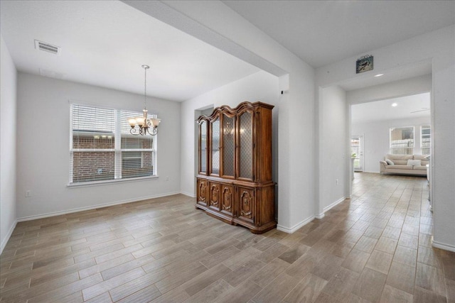 unfurnished dining area featuring a chandelier, wood finished floors, and baseboards