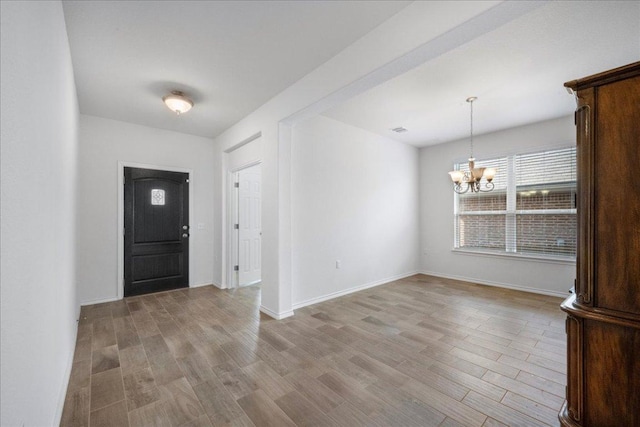 entrance foyer with a chandelier, light wood finished floors, and baseboards