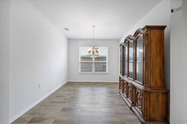unfurnished dining area with a chandelier, baseboards, and wood finished floors