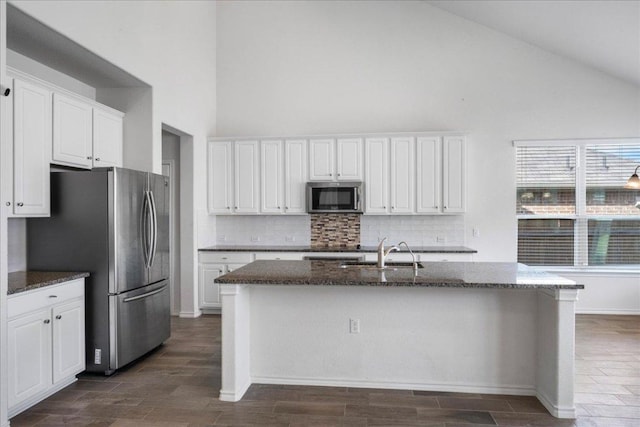 kitchen with stainless steel appliances, high vaulted ceiling, a sink, tasteful backsplash, and white cabinetry