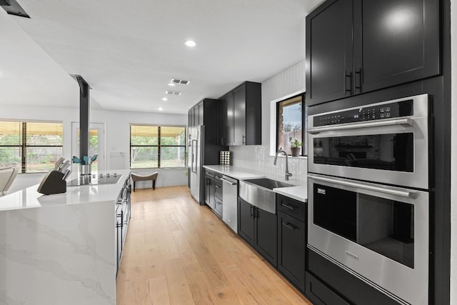 3305 Eldorado Trl, Austin, TX 78748 - kitchen featuring stainless steel appliances, dark cabinetry, a sink, light wood-style floors, and recessed lighting