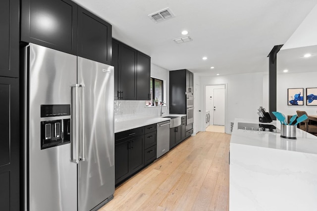 3305 Eldorado Trl, Austin, TX 78748 - kitchen with stainless steel appliances, dark cabinets, light wood finished floors, a sink, and recessed lighting