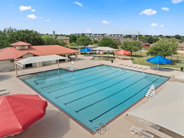 community pool with fence, a patio area, and a residential view
