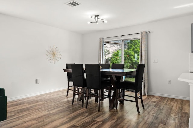 dining space with wood finished floors, baseboards, and a chandelier