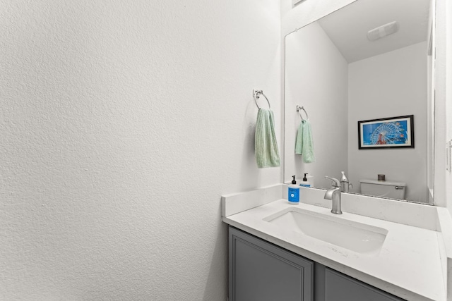 bathroom with vanity, a textured wall, and toilet