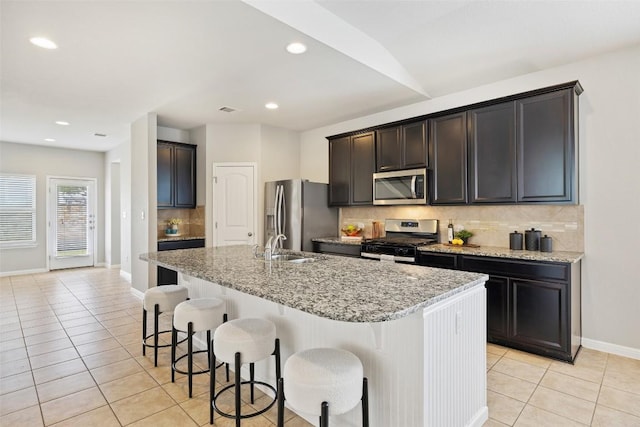 801 Vaughn St, Georgetown, TX 78628 - kitchen with stainless steel appliances, light tile patterned flooring, backsplash, an island with sink, and a kitchen breakfast bar