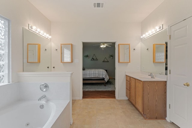 full bath featuring ceiling fan, a jetted tub, connected bathroom, vanity, and baseboards