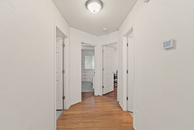 corridor featuring light wood finished floors and baseboards
