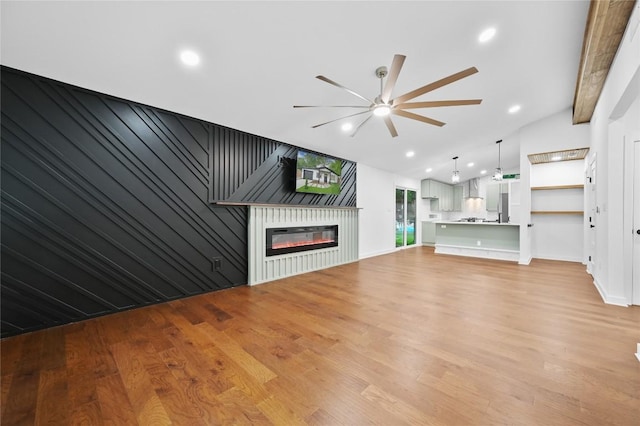 1006 Cherico St, Austin, TX 78702 - unfurnished living room with ceiling fan, light wood-style flooring, lofted ceiling, a glass covered fireplace, and recessed lighting