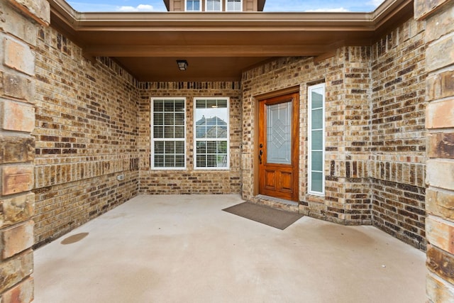 property entrance featuring brick siding and a patio
