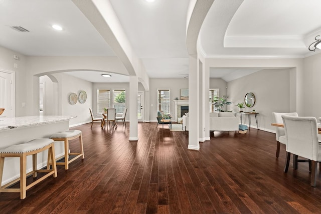foyer entrance featuring dark wood finished floors, arched walkways, crown molding, baseboards, and recessed lighting
