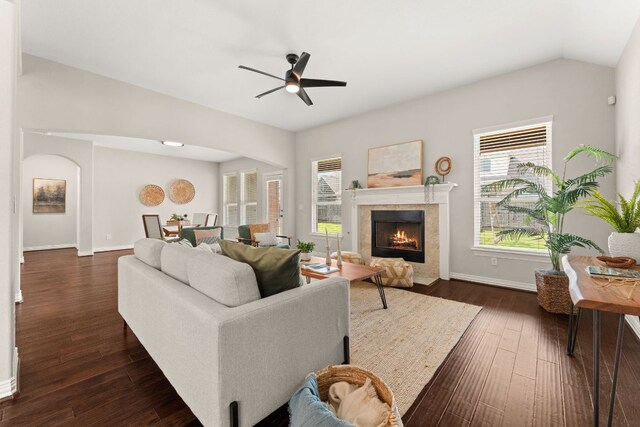living room featuring plenty of natural light, arched walkways, baseboards, dark wood-style floors, and vaulted ceiling