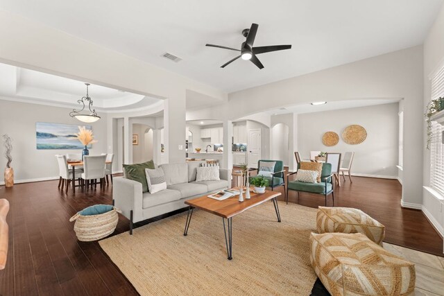 living area featuring arched walkways, wood finished floors, ceiling fan, and baseboards