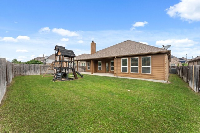 rear view of house featuring a playground, a chimney, a patio, and roof with shingles