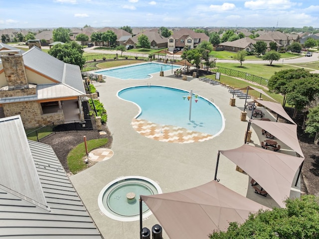 community pool with fence, a residential view, and a hot tub
