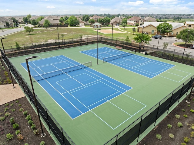 view of tennis court with fence and a residential view