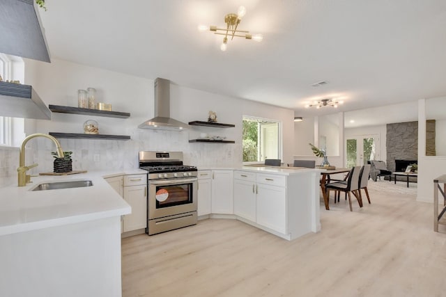 4011 Eskew Dr, Austin, TX 78749 - kitchen featuring open shelves, stainless steel range with gas stovetop, a sink, wall chimney exhaust hood, and light wood finished floors